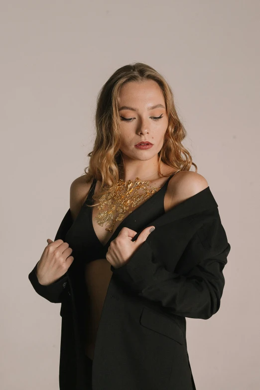 a woman in black shirt and jacket with large gold necklace