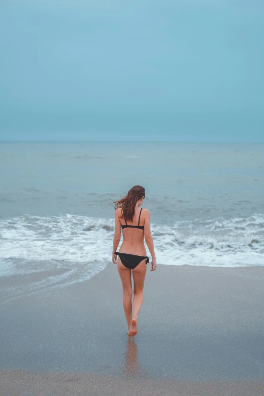 a person walks on the beach towards the ocean