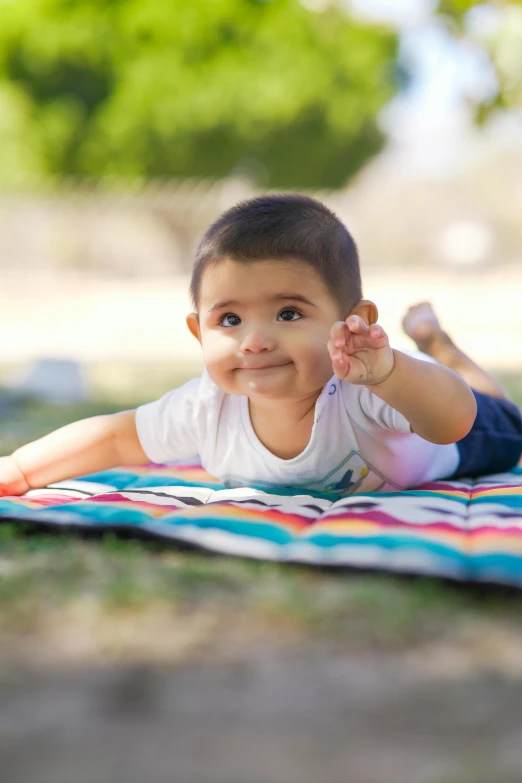 a little boy laying on top of a colorful blanket