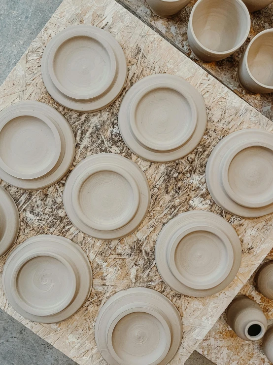 a bunch of plates in a row on a wooden table