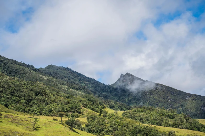 a hill with a few clouds hovering by