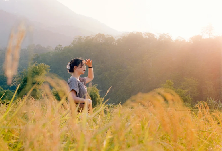 a girl in a field drinking water from a glass