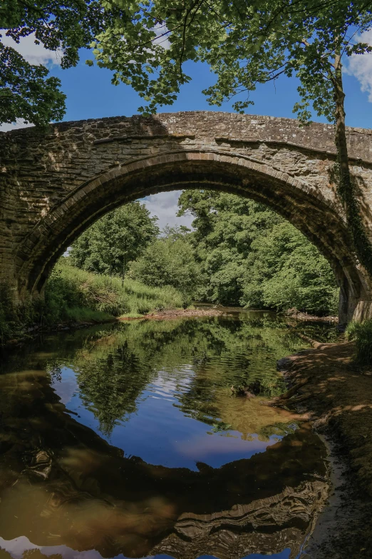 an arched stone bridge over a stream