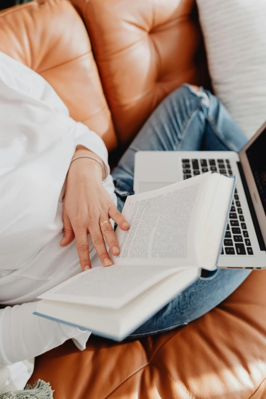 a woman in a white shirt on a couch with a laptop