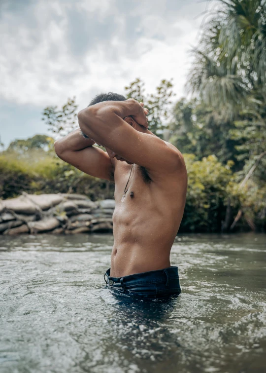 a man in a black swimming trunks stands in water