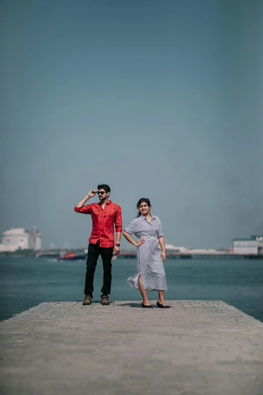 a man and woman standing next to the ocean