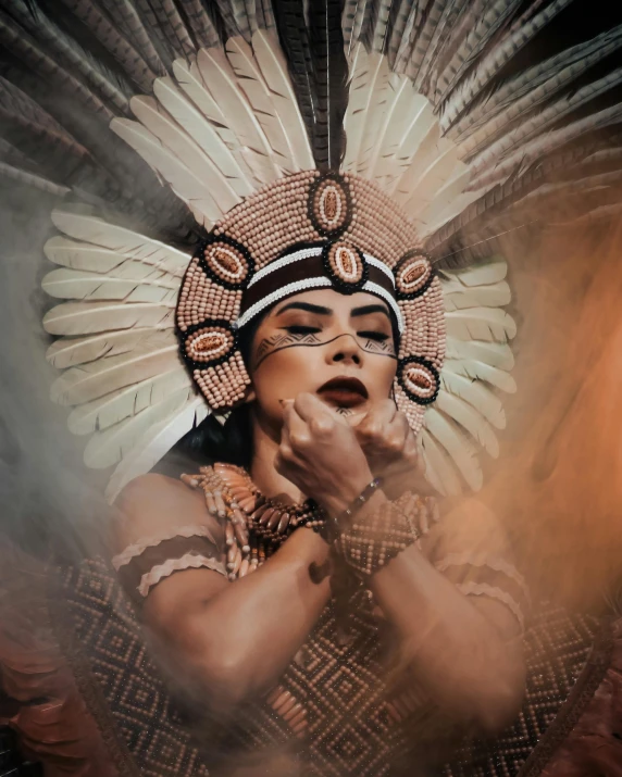 a woman wearing an indian head dress holding her face