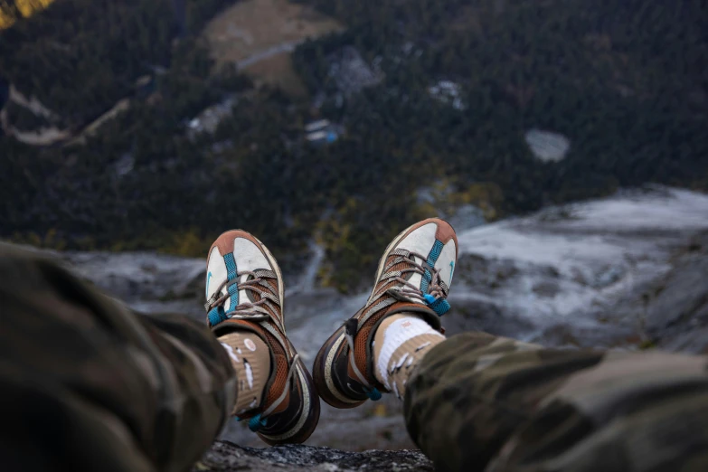 someone's feet hanging down from a high altitude view of a mountain