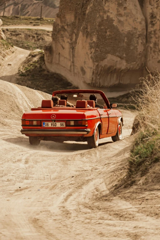 a car driving on the dirt road near a rock formation