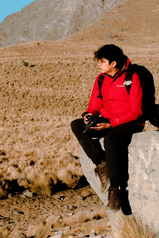 a man wearing a backpack and sitting on a rock