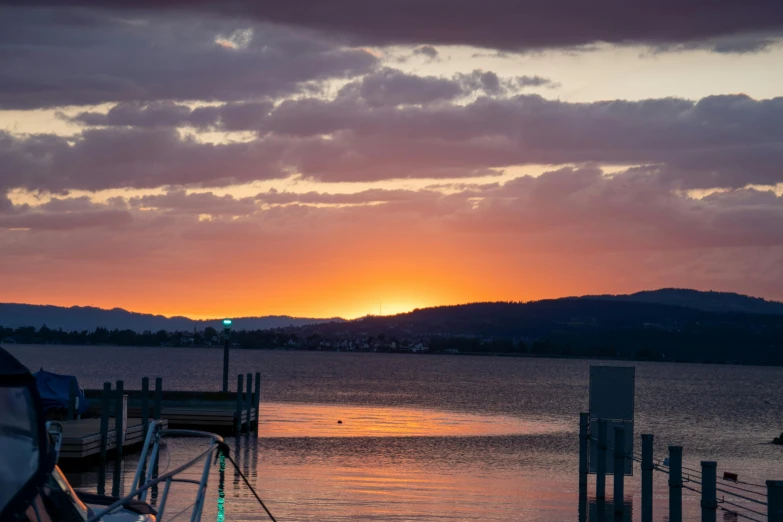 the sun is setting over the mountains on the water