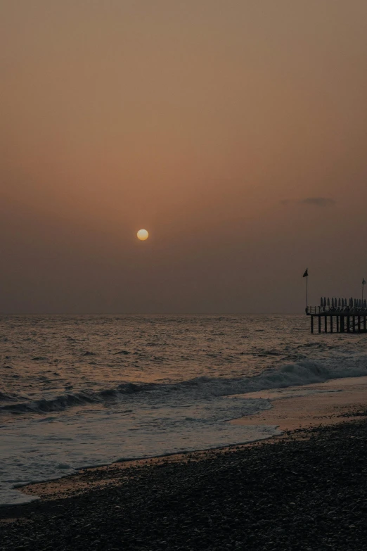 a sunset over a beach with a boat at the edge