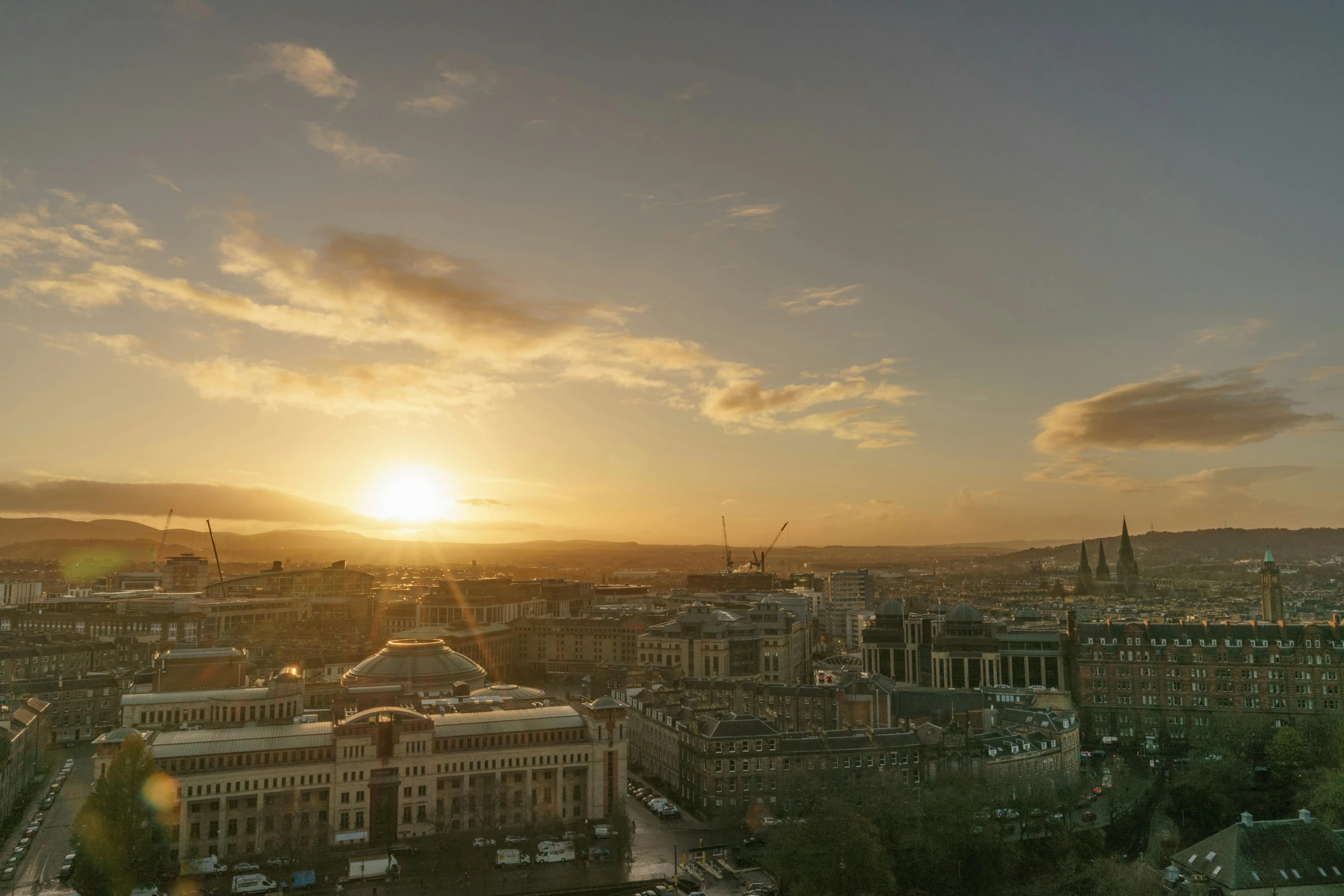 a po taken from the top of a building shows sun behind clouds in a blue sky