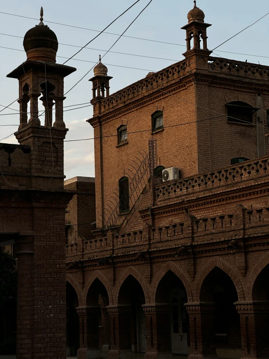 two towers with a clock sitting near some buildings