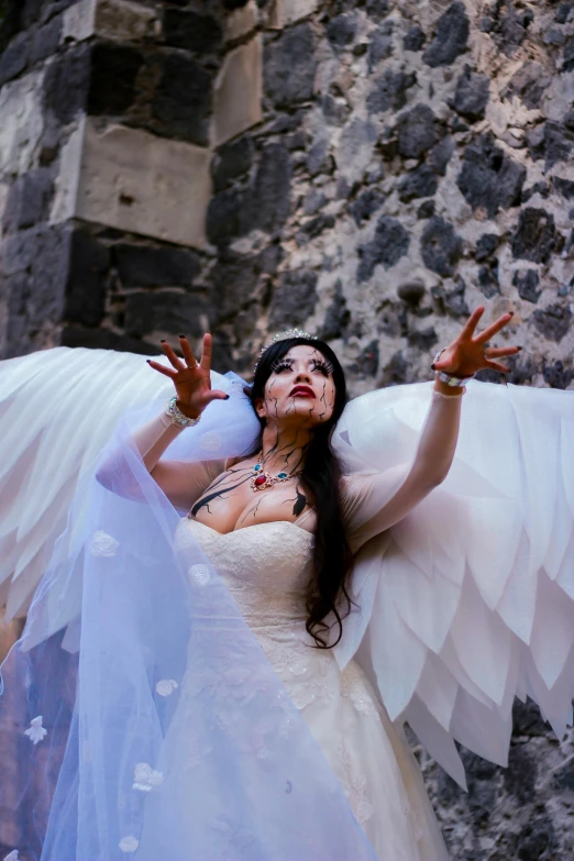 a beautiful woman dressed in a white wedding gown with large white wings