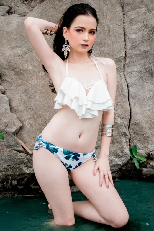 young lady in swimwear posing in the water by rocks