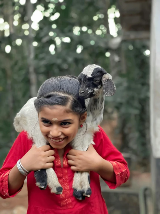 the girl smiles as she holds a large animal on her shoulder