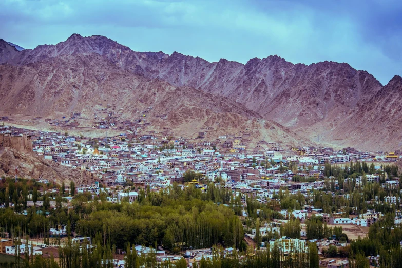 a mountain with houses in the bottom with mountains behind it