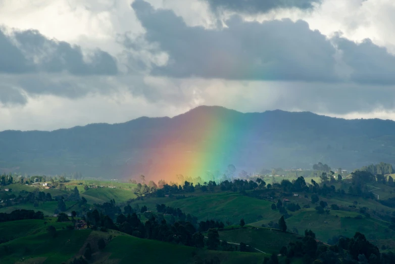 the colorful rainbow is visible over the hills