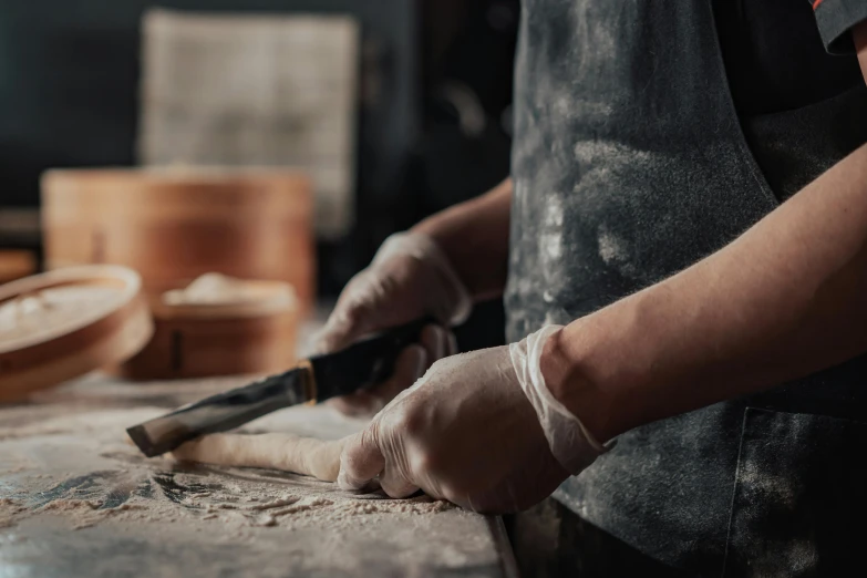 person using long handle to sharpe knife on a table