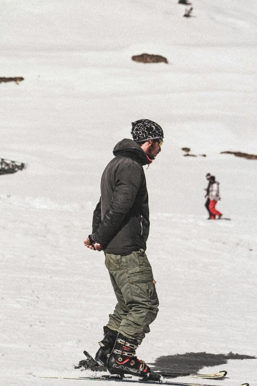 a person with a beanie standing on a snow board in the snow