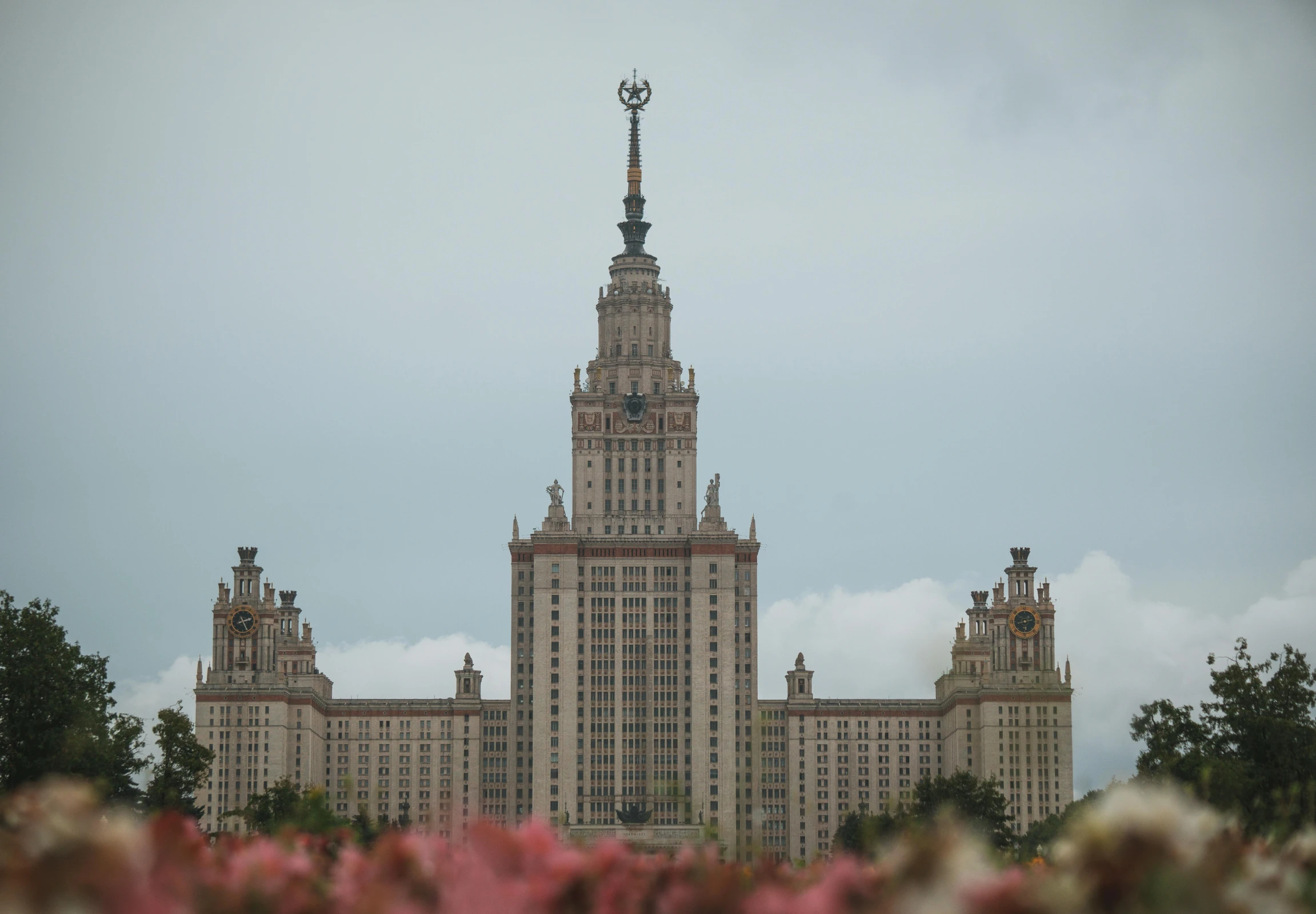 two tall buildings with many windows that are set back against a cloudy sky