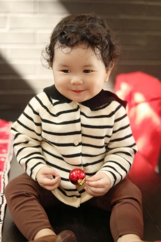 a young baby sitting on a table next to a black cat