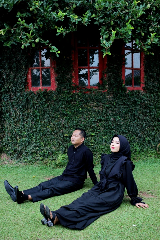 two men dressed in black are lying on the grass