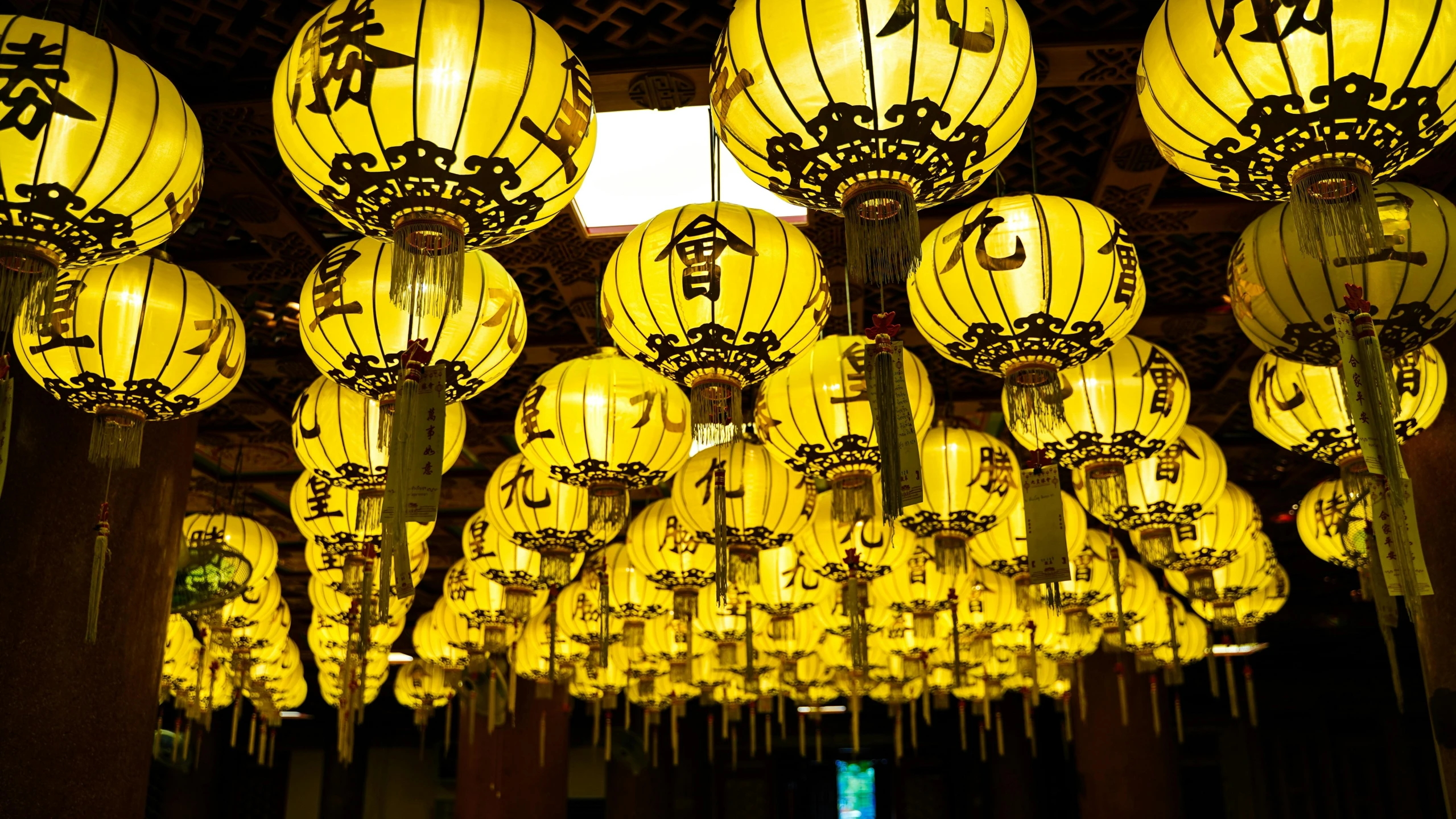 large yellow lanterns hang from the ceiling in a hall