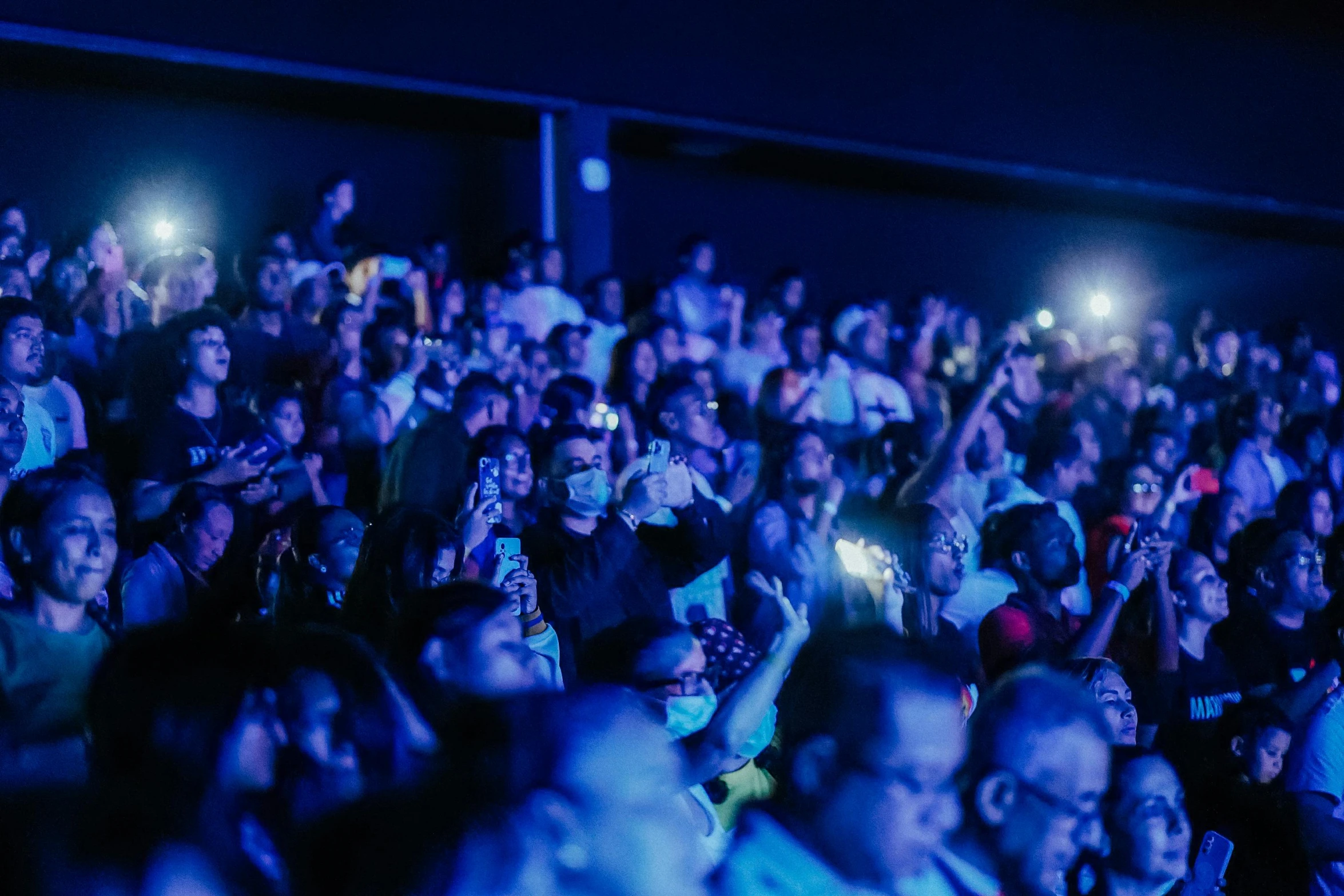 a crowded room full of people clapping with cell phones