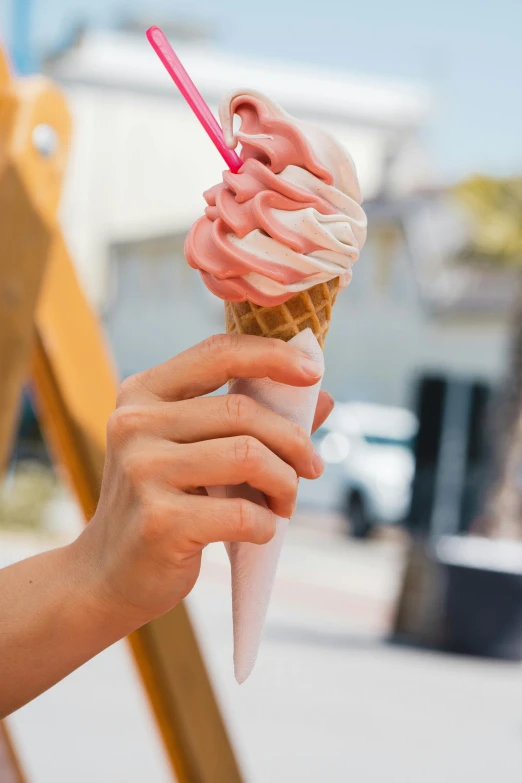 someone holding an ice cream cone with icing in their hand