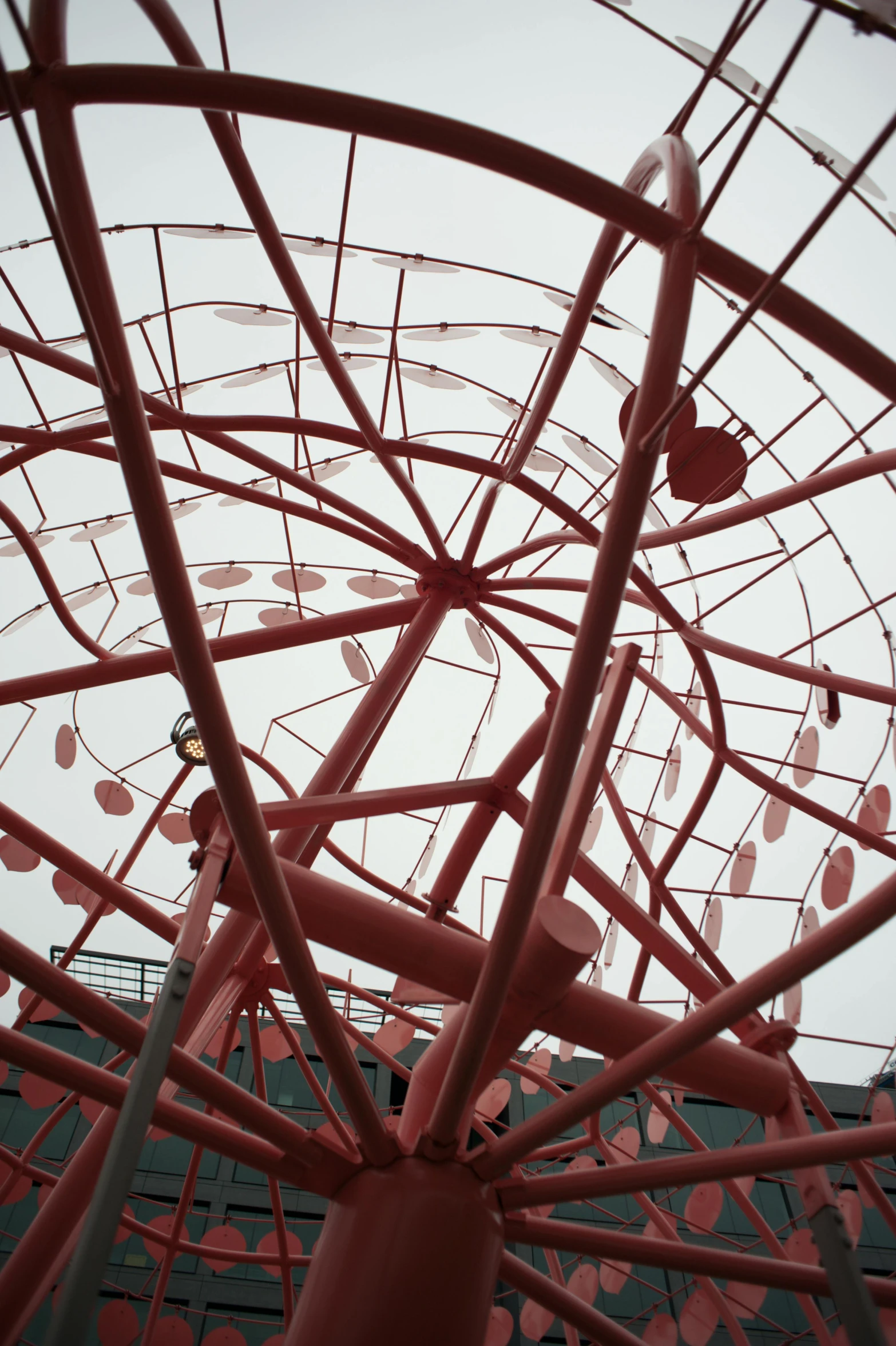 red plastic sculpture against a white sky and building