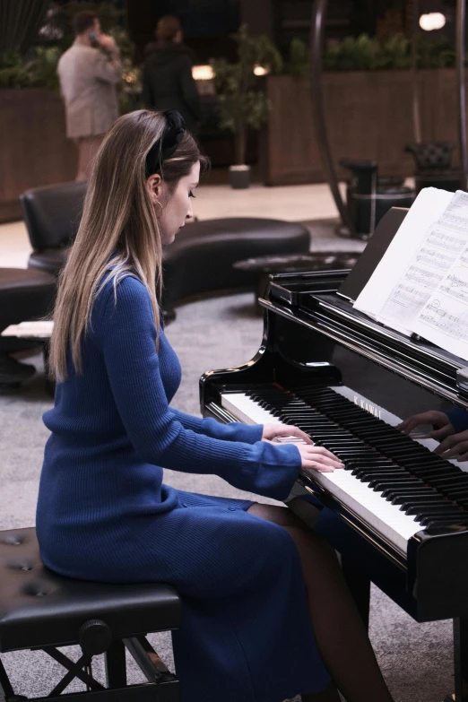 a woman sitting at a piano while playing it