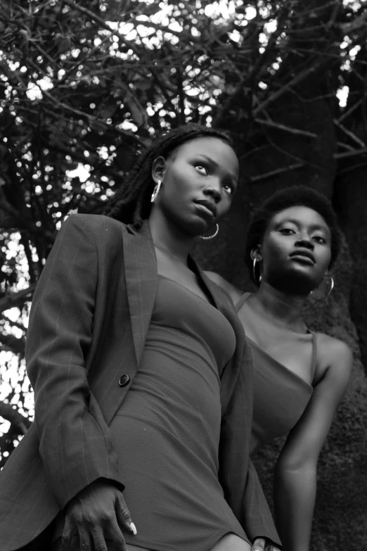 two black women standing by the tree in front of the camera