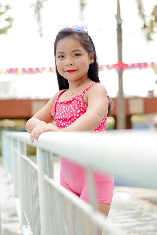 little girl posing for the camera near a fence