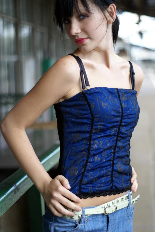 a woman wearing a blue shirt and jeans standing on a bench