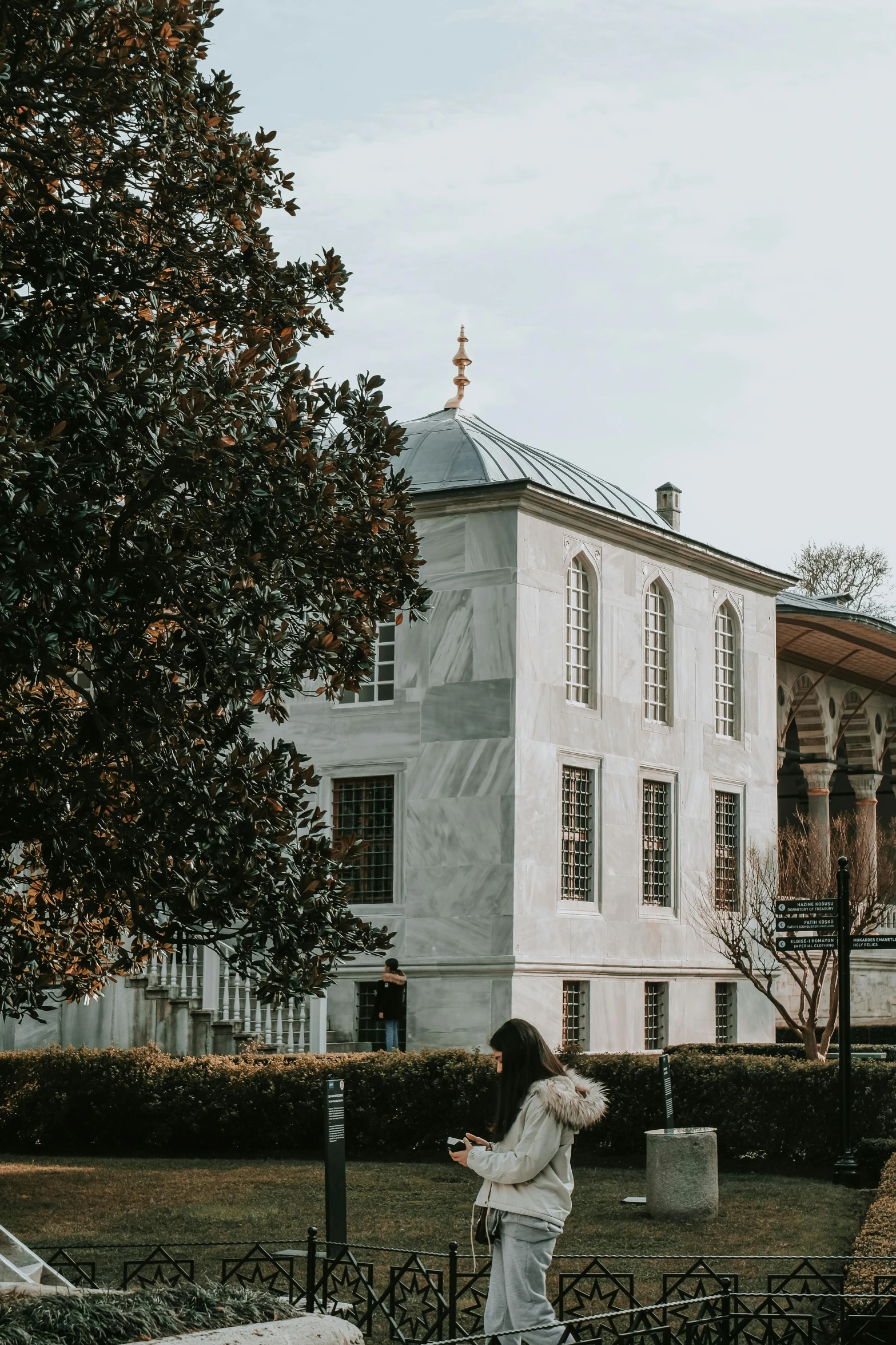 a woman riding a skateboard down a street past a white building