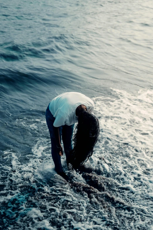 a man kneeling down on top of water in the ocean