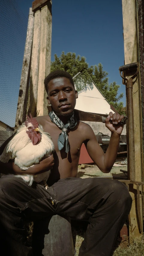 the man in black pants and tie is holding a chicken