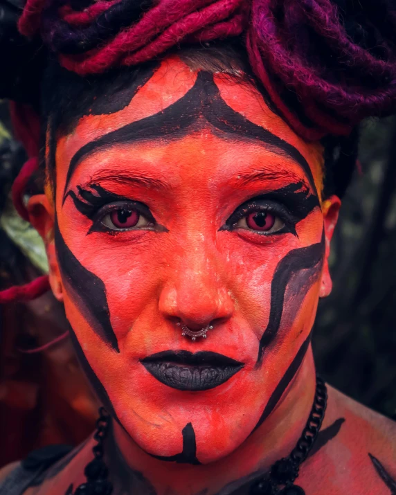a woman with black and orange makeup looks at the camera