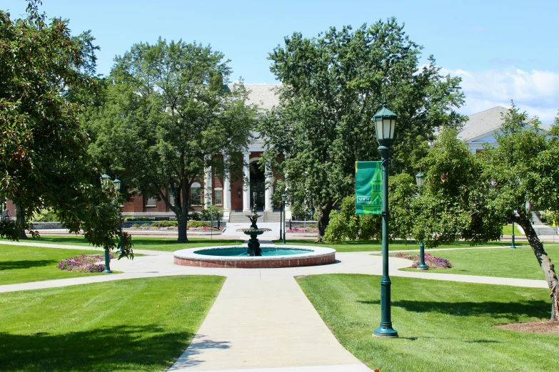 a statue sits in the middle of a circle in a lawn surrounded by trees