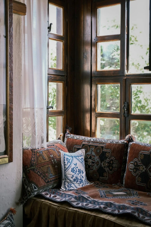 a window seat with pillows on it sitting in front of some windows