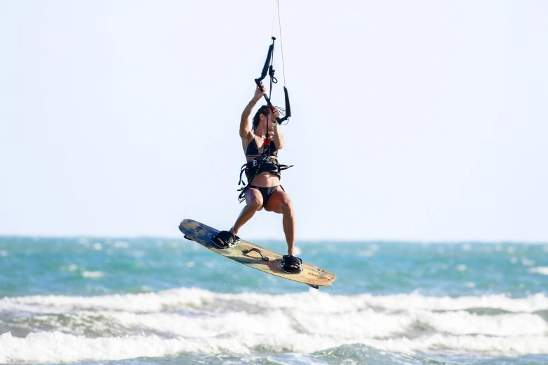 a woman on water skis holds onto the handle of a parachute