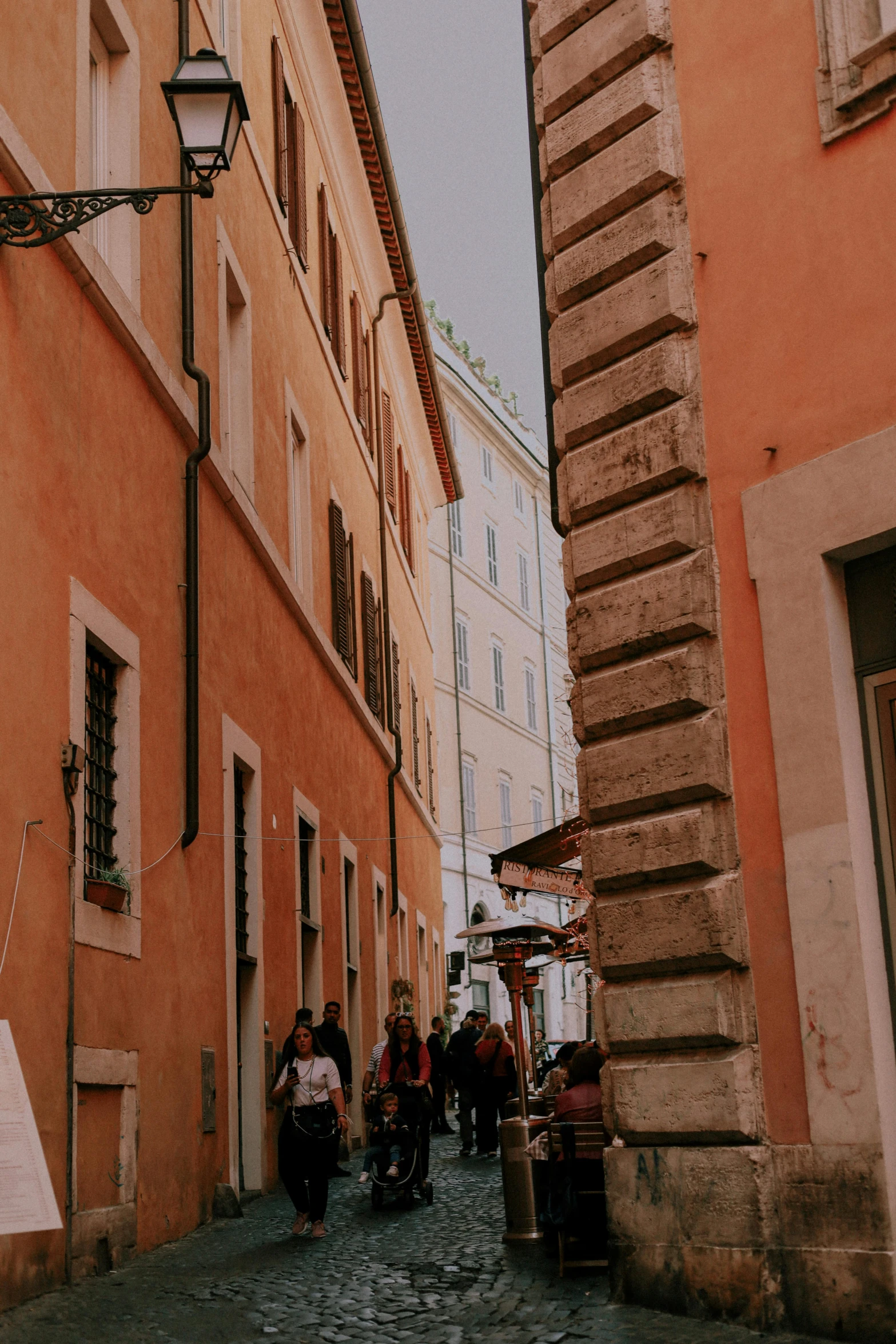 people walking on a cobblestone street next to a tall building