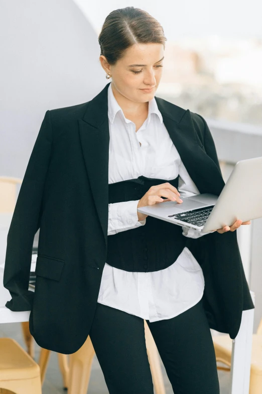 a woman sits at a table and uses her laptop