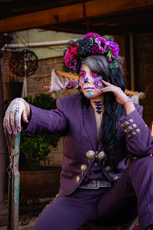 a woman in halloween makeup sits with her face painted