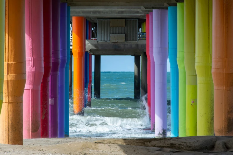 rainbow colored columns near the ocean with blue sky