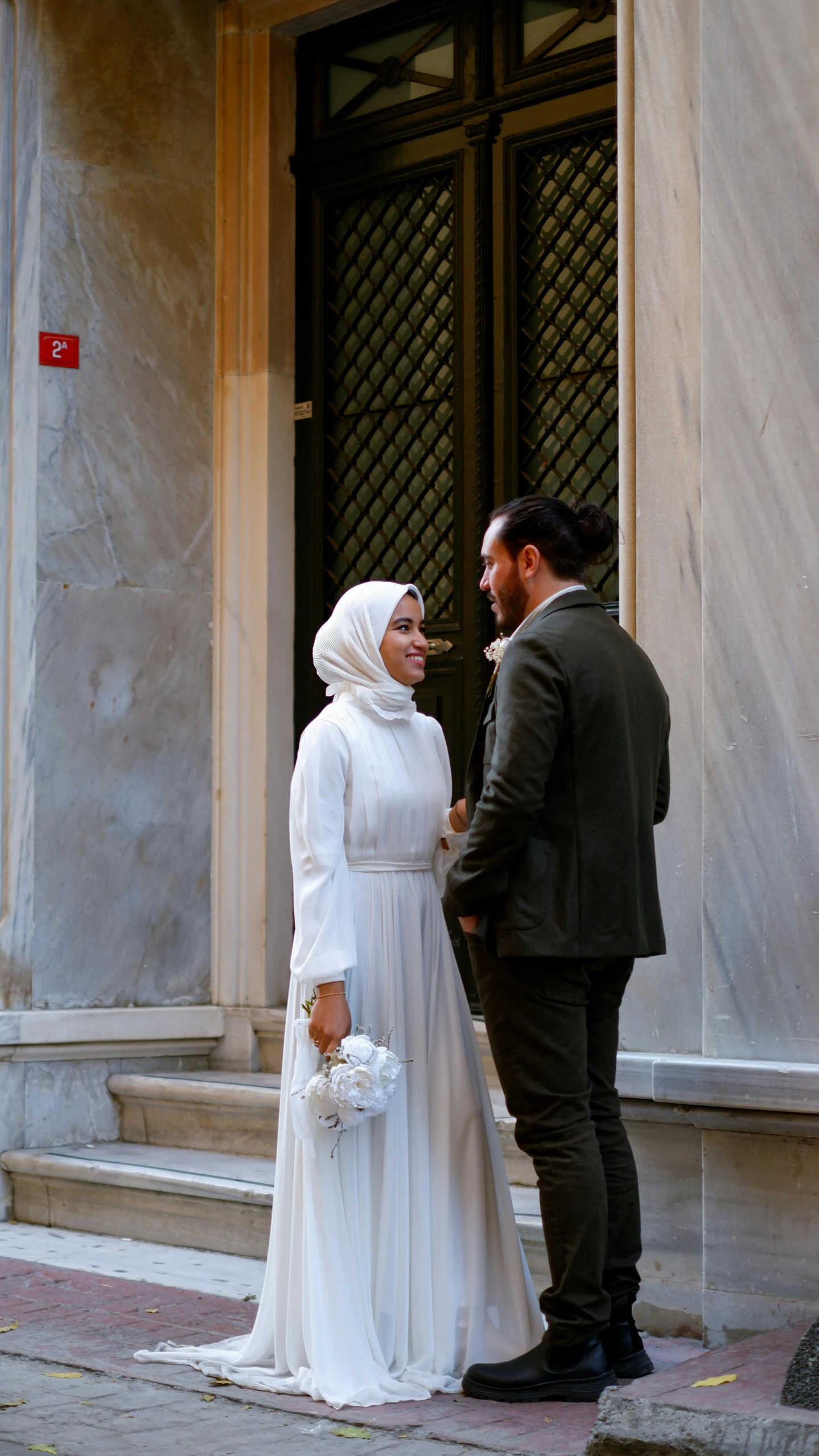 a man and woman dressed in wedding outfits are outside a building