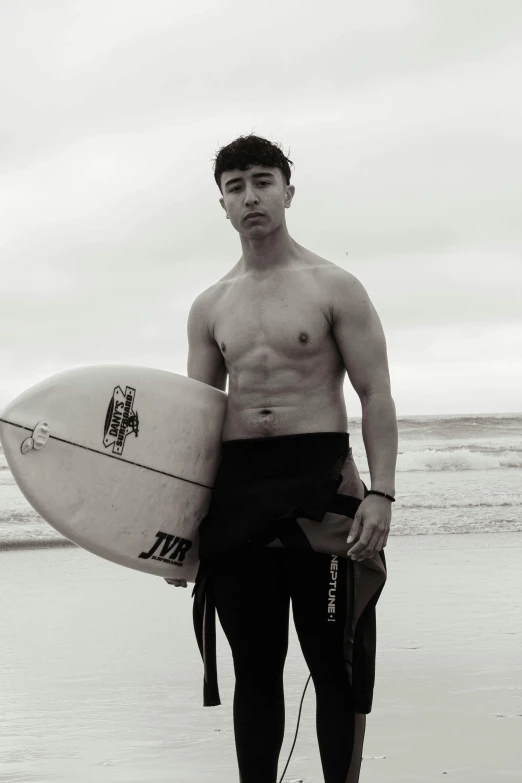 a man standing at the beach holding a surfboard