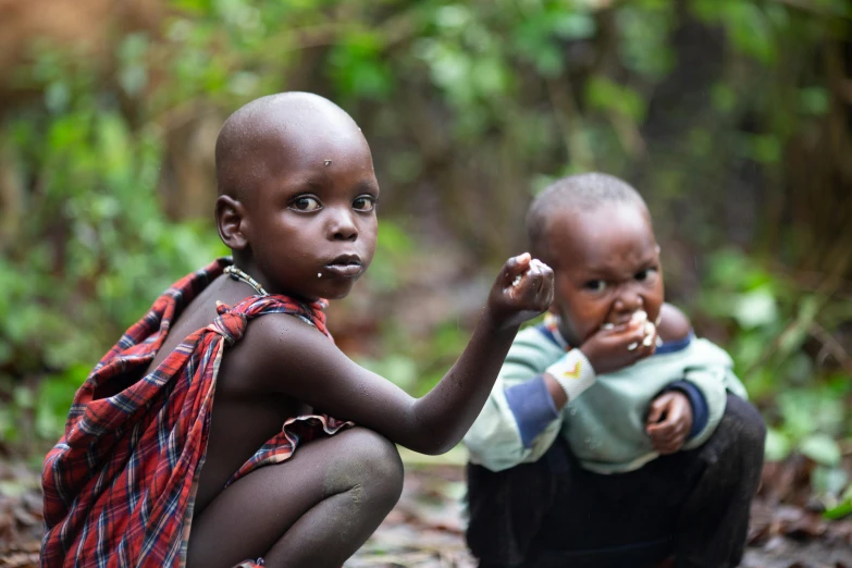 two children in native clothing are crouched down